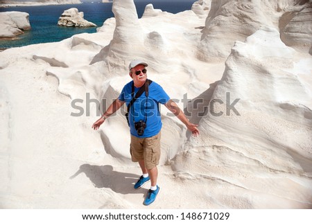 Adult man explore the caves and rock formations by the sea at Sarakiniko area on Milos island, Greece