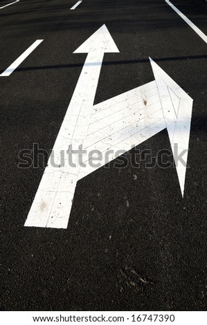 The white direction arrows on the black asphalt road.