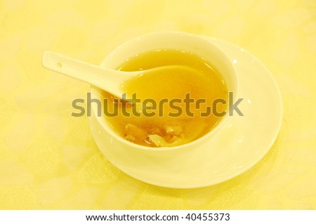 A serving of meat soup in porcelain bowl with spoon.