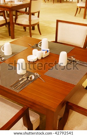 Hotel cafeteria wood table and leather chairs with table setting.
