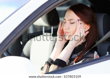 Woman with headache in a car