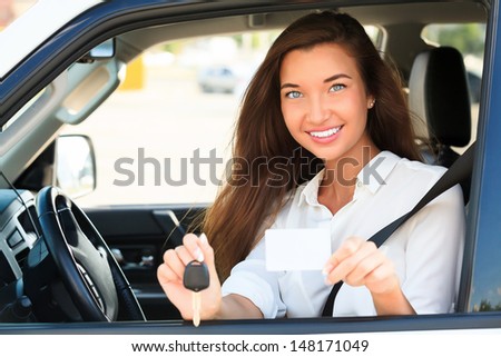 girl in a car showing a key and an empty white card