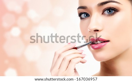 woman applying lips makeup with cosmetic brush on pastel blurred background copyspace woman applying lips makeup with cosmetic brush on pastel blurred background copyspace