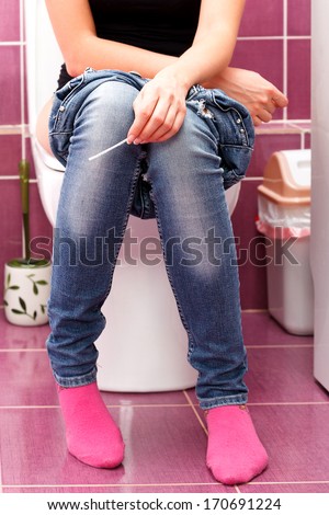 woman with a pregnancy test in a toilet