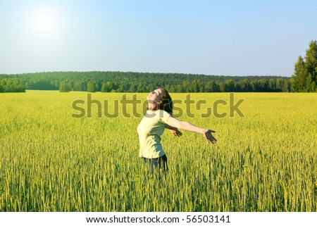 woman with open arms in the green cereal field.