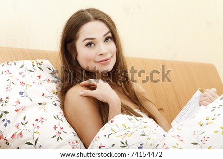 Beautiful woman reading a book while laying in a bed