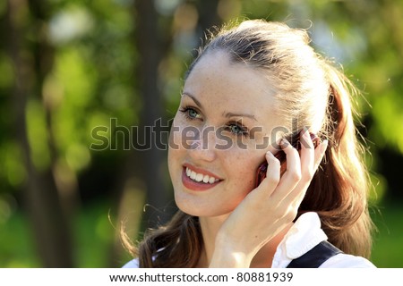 Young smiling woman speaks by mobile phone