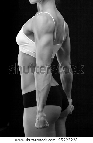 Black and white portrait of female fitness bodybuilder posing against black background