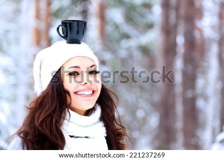 Happy woman with a cup of hot tea on her head