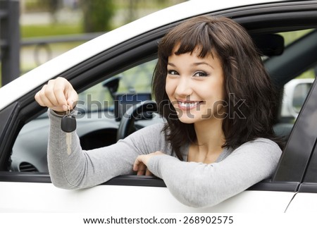 Pretty female driver in a white car showing the car key