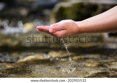 The hands taking out the water from the river