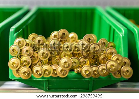 Many yellow screws in the green plastic box