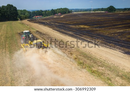 The tractor harrowing the large field to stop the fire