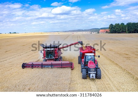Aerial view on the combines and tractors working on the large wheat field