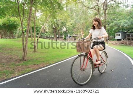 A pretty girl in white T-shirt practice  to ride bicycle at Suan Rot Fai park in Bangkok city, Thailand.