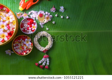Thai traditional jasmine garland and Colorful flower in water bowls decorating and scented water, perfume, marly limestone, pipe gun on Banana leaf for Songkran Festival or Thai New Year.