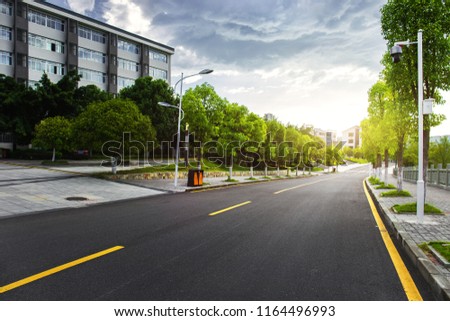 Beautiful university campus, clean asphalt roads, lush trees and newly built school buildings, illuminated by the sun in the summer