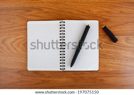 Notepad with a spiral binding and checkered sheets on a wooden background