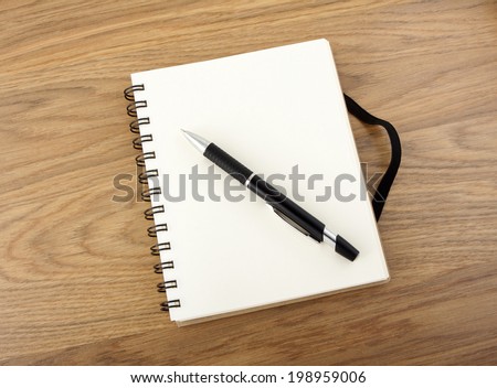 Recycled paper notebook with black elastic band and pen on a table