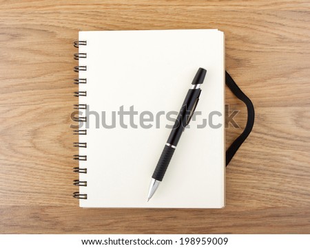Recycled paper notebook with black elastic band and pen on a table