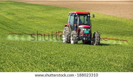 Farmer spraying wheat field at spring season, herbicides, pesticides