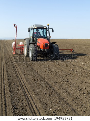 Farmer in tractor sowing corn maize crops