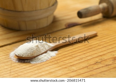 Table spoon with flour on wooden bakery table