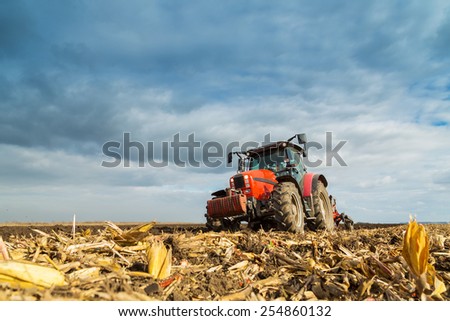 Farmer plowing with red tractor