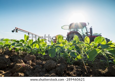 Tractor spraying soybean crops with pesticides and herbicides