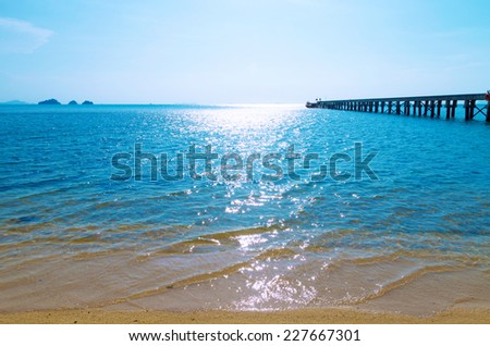 Wooden bridge to the sea in Koh Samui, Thailand. Glare on the blue sea water. Sandy beach and uninhabited islands.