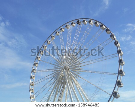 giant wheel provides rides for viewing the city White clouds in the blue sky in background