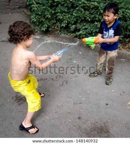 PARIS - JULY 18 - Two unidentified young boys try to beat the days-long heatwave in Paris with a water fight at Place des Abbesses, on the slope of Montmartre, on July 18, 2013 in Paris.