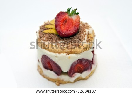 Strawberry cheesecake with mascarpone cream decorated with chocolate chips and a half a strawberry