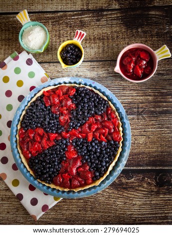 Berry tart with strawberries and blueberries on wooden table and on fabric with color dots