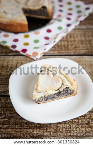Slice of homemade poppy seed and custard pie with pastry hearts on fabric with color dots