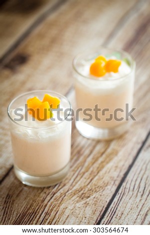 Peach souffle or mousse in glasses decorated with pieces of peach on wood background
