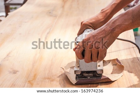 Hand of worker sanding the old wood table.