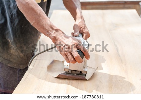 Hand of worker sanding the old wood table.