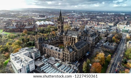 Low level aerial image over the autumn foliage of trees in Kelvingrove Park, Glasgow, to the gothic tower of Glasgow University with the cityscape behind.