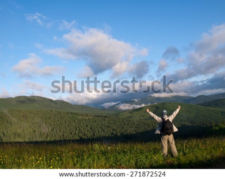 On the top of world, man standing on mountain top. His arms is up to sky.