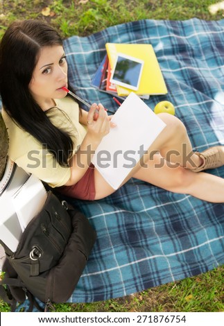 Student on campus with books and pad.