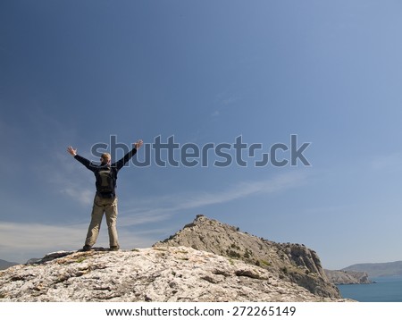 On the top of world, man standing on a rock. His arms is up to sky.