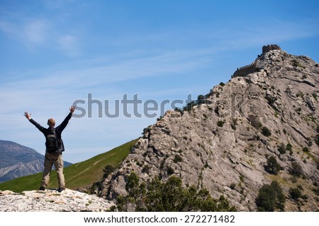 Happy man standing on the top of mount with his arms raised to the sky.