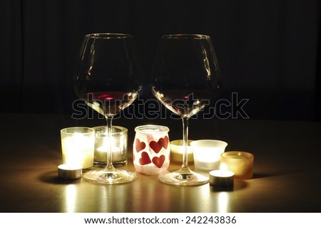 Two glasses of wine, by candle light, with a romantic theme