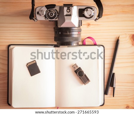 Retro vintage old photo camera with notebook, pen, pendrive, sd card and mouse on a wooden table
