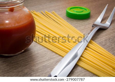 Spaghetti pasta, tomato sauce and fork on a wooden background