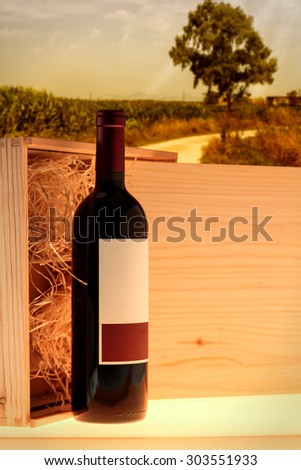 Wooden case with red wine bottle on countryside