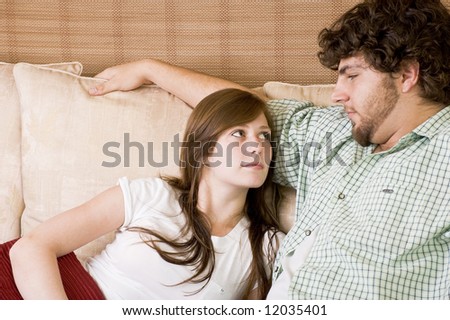 Young couple relaxing on a couch, looking each other in the eyes.