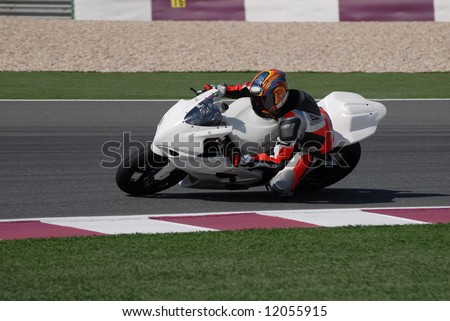 Racing bike rider leaning into a fast corner on track day.