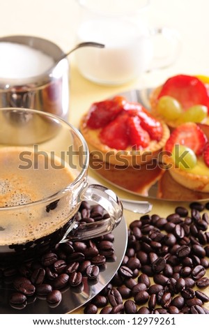 Freshly brewed coffee with a selection of pastries and cakes. Coffee beans are scattered for extra effect.